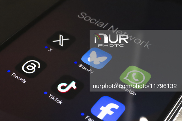 The logos of the social networks X (Twitter), Bluesky, WhatsApp, Threads, TikTok, and Facebook are displayed on the screen of a smartphone i...