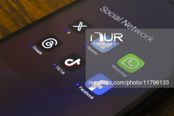 The logos of the social networks X (Twitter), Bluesky, WhatsApp, Threads, TikTok, and Facebook are displayed on the screen of a smartphone i...