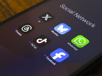 The logos of the social networks X (Twitter), Bluesky, WhatsApp, Threads, TikTok, and Facebook are displayed on the screen of a smartphone i...