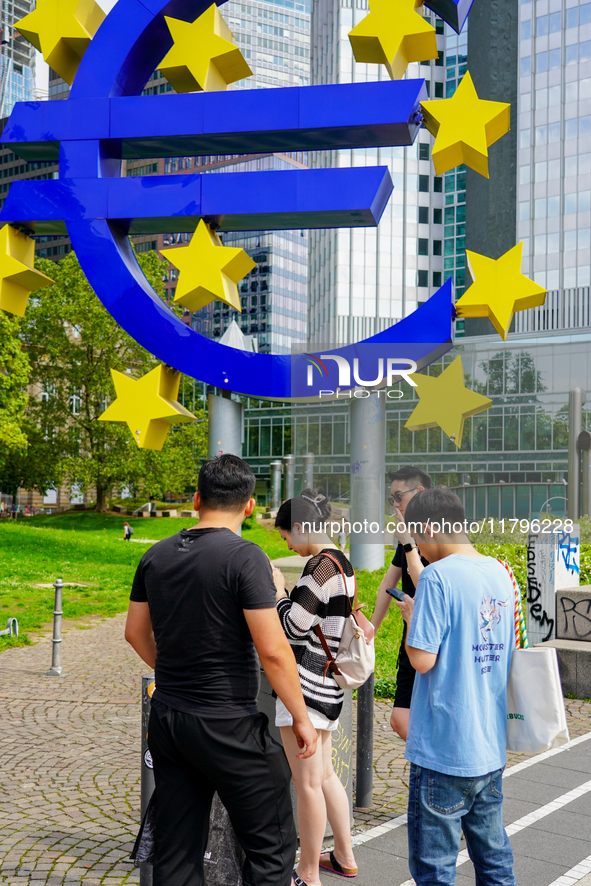 Visitors gather around the iconic 14-meter-high Euro sculpture by Ottmar Horl at Willy-Brandt-Platz in Frankfurt am Main, Germany, on August...