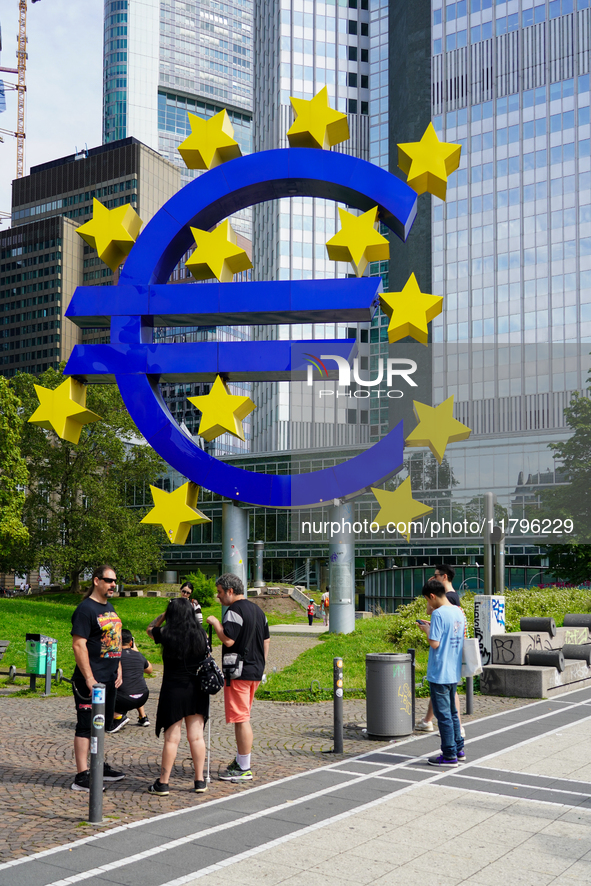 Visitors admire the monumental Euro sculpture by Ottmar Horl, located at Willy-Brandt-Platz in Frankfurt am Main, Germany, on August 15, 202...