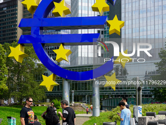 Visitors admire the monumental Euro sculpture by Ottmar Horl, located at Willy-Brandt-Platz in Frankfurt am Main, Germany, on August 15, 202...