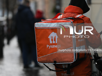 A courier from Pyszne.pl on a bike is seen on the street in Krakow, Poland, on November 18, 2024. (