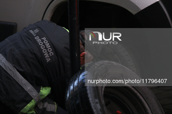 A roadside assistance worker changes a tire on a car on the street in Krakow, Poland, on November 18, 2024. 