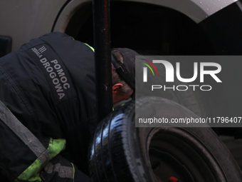 A roadside assistance worker changes a tire on a car on the street in Krakow, Poland, on November 18, 2024. (