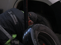 A roadside assistance worker changes a tire on a car on the street in Krakow, Poland, on November 18, 2024. (