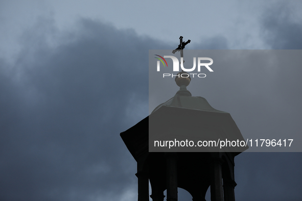 A church tower with a cross in the sky is visible on the street in Krakow, Poland, on November 18, 2024. 