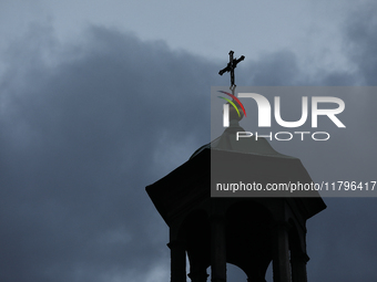 A church tower with a cross in the sky is visible on the street in Krakow, Poland, on November 18, 2024. (