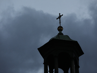 A church tower with a cross in the sky is visible on the street in Krakow, Poland, on November 18, 2024. (