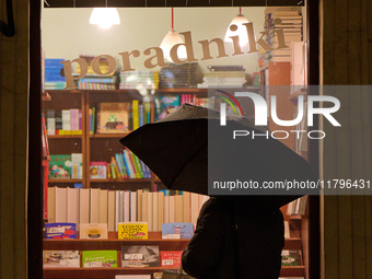 A woman with an umbrella is seen looking at a book shop window in Warsaw, Poland on 20 November, 2024. (