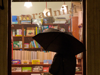 A woman with an umbrella is seen looking at a book shop window in Warsaw, Poland on 20 November, 2024. (