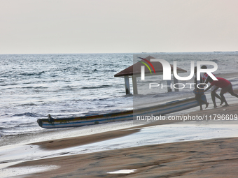 Fishermen push a fishing boat into the ocean along Paruthiyoor Beach in Paruthiyoor, Kerala, India, on April 15, 2024. (