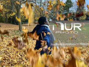 A woman throws colorful fallen leaves in the air during the autumn season in Toronto, Ontario, Canada, on November 6, 2024. (