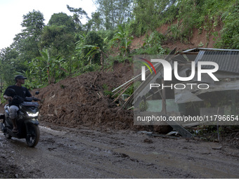 Residents on motorbikes cross a road section covered by landslide material after a flash flood and landslide hit Mekarbuana village, Karawan...