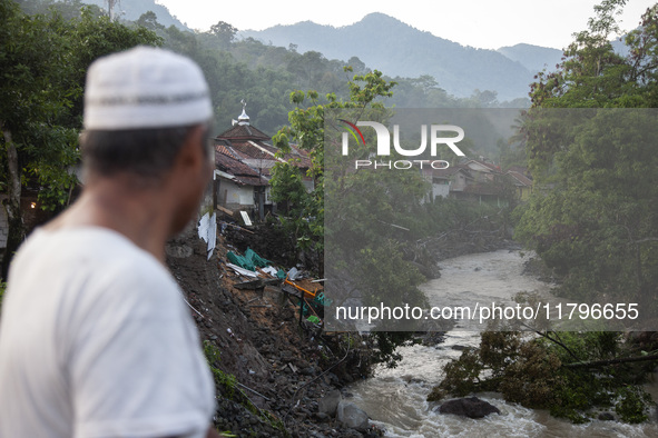 A resident watches damaged houses and fallen trees from a bridge after a flash flood and landslide hit Mekarbuana village, Karawang district...