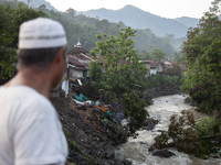 A resident watches damaged houses and fallen trees from a bridge after a flash flood and landslide hit Mekarbuana village, Karawang district...