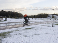 People spotted on their bicycle during with the snow around them. First winter weather of the season with snow hit the Netherlands. Low temp...