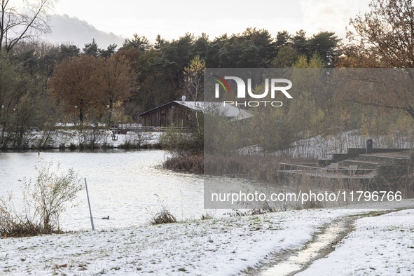 The lake and a wooden building in front of the forest in Park Meerland. First winter weather of the season with snow hit the Netherlands. Lo...