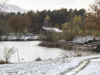 The lake and a wooden building in front of the forest in Park Meerland. First winter weather of the season with snow hit the Netherlands. Lo...