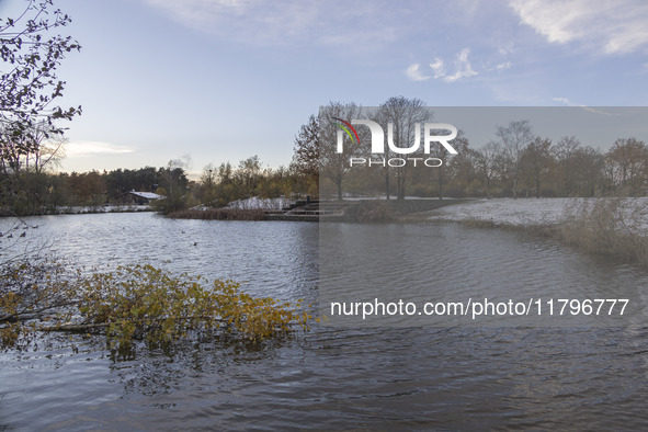 The lake and a wooden building in front of the forest in Park Meerland. First winter weather of the season with snow hit the Netherlands. Lo...