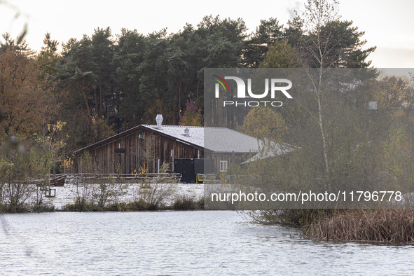 The lake and a wooden building in front of the forest in Park Meerland. First winter weather of the season with snow hit the Netherlands. Lo...