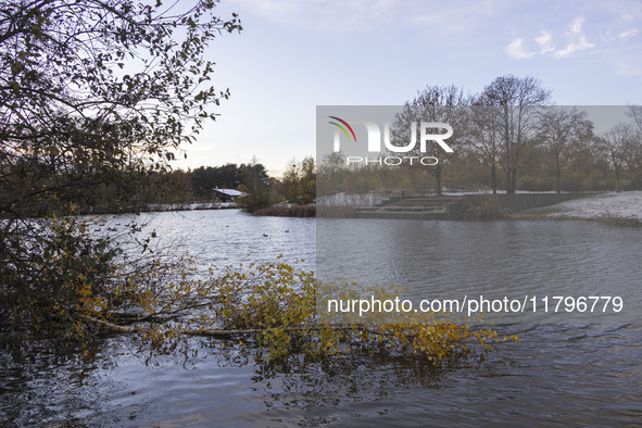 The lake and a wooden building in front of the forest in Park Meerland. First winter weather of the season with snow hit the Netherlands. Lo...