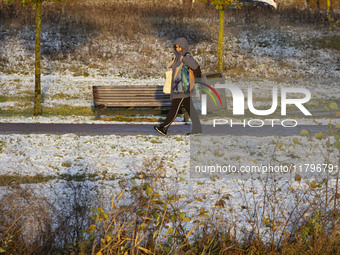 A woman is walking on the road carrying groceries. First winter weather of the season with snow hit the Netherlands as spotted before the su...