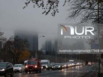 Vehicles make their way along Bloor Street East in foggy weather in Toronto, Ontario, on November 20, 2024. (