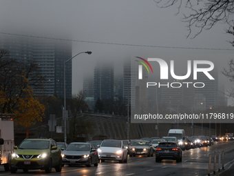 Vehicles make their way along Bloor Street East in foggy weather in Toronto, Ontario, on November 20, 2024. (