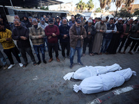 People pray next to the bodies of Palestinians killed in an Israeli strike at Al-Aqsa Martyrs Hospital in Deir Al-Balah, in the central Gaza...