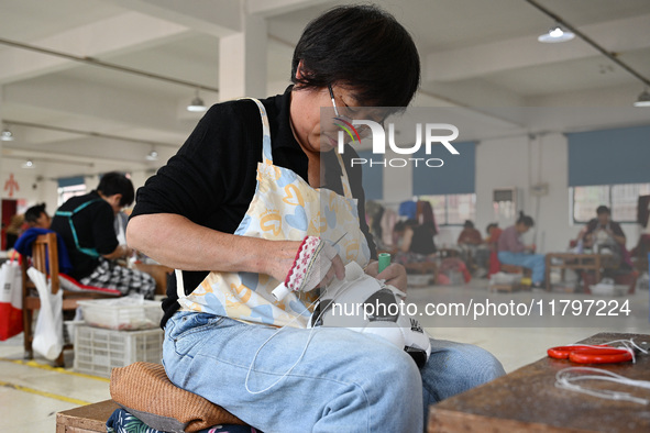 Workers make footballs by hand for export to overseas markets such as Japan at a sports goods factory in Suqian, Jiangsu province, China, on...