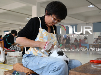 Workers make footballs by hand for export to overseas markets such as Japan at a sports goods factory in Suqian, Jiangsu province, China, on...