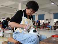 Workers make footballs by hand for export to overseas markets such as Japan at a sports goods factory in Suqian, Jiangsu province, China, on...