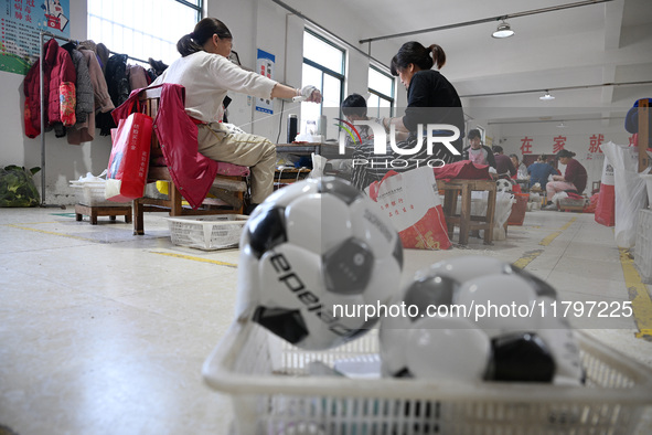 Workers make footballs by hand for export to overseas markets such as Japan at a sports goods factory in Suqian, Jiangsu province, China, on...