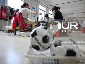 Workers make footballs by hand for export to overseas markets such as Japan at a sports goods factory in Suqian, Jiangsu province, China, on...