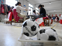 Workers make footballs by hand for export to overseas markets such as Japan at a sports goods factory in Suqian, Jiangsu province, China, on...