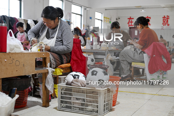 Workers make footballs by hand for export to overseas markets such as Japan at a sports goods factory in Suqian, Jiangsu province, China, on...