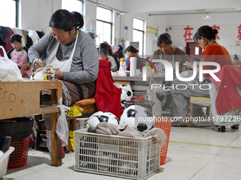 Workers make footballs by hand for export to overseas markets such as Japan at a sports goods factory in Suqian, Jiangsu province, China, on...