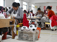 Workers make footballs by hand for export to overseas markets such as Japan at a sports goods factory in Suqian, Jiangsu province, China, on...