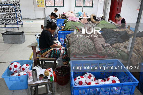 Workers make footballs by hand for export to overseas markets such as Japan at a sports goods factory in Suqian, Jiangsu province, China, on...