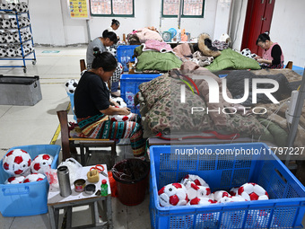 Workers make footballs by hand for export to overseas markets such as Japan at a sports goods factory in Suqian, Jiangsu province, China, on...