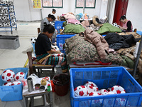 Workers make footballs by hand for export to overseas markets such as Japan at a sports goods factory in Suqian, Jiangsu province, China, on...