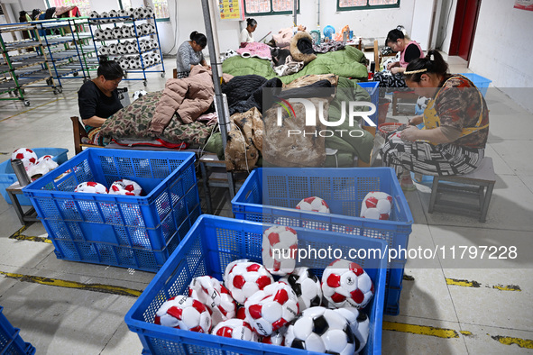 Workers make footballs by hand for export to overseas markets such as Japan at a sports goods factory in Suqian, Jiangsu province, China, on...