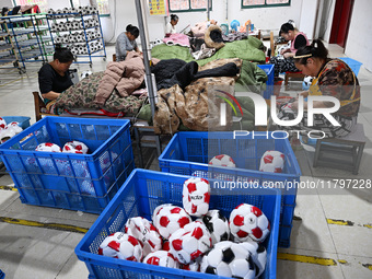 Workers make footballs by hand for export to overseas markets such as Japan at a sports goods factory in Suqian, Jiangsu province, China, on...