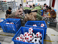 Workers make footballs by hand for export to overseas markets such as Japan at a sports goods factory in Suqian, Jiangsu province, China, on...