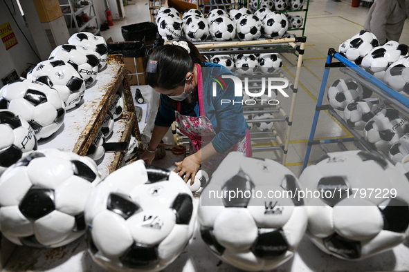 Workers make footballs by hand for export to overseas markets such as Japan at a sports goods factory in Suqian, Jiangsu province, China, on...