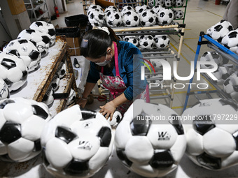 Workers make footballs by hand for export to overseas markets such as Japan at a sports goods factory in Suqian, Jiangsu province, China, on...