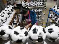 Workers make footballs by hand for export to overseas markets such as Japan at a sports goods factory in Suqian, Jiangsu province, China, on...