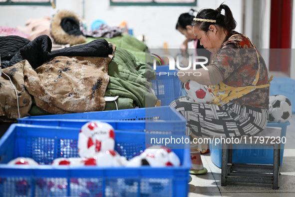 Workers make footballs by hand for export to overseas markets such as Japan at a sports goods factory in Suqian, Jiangsu province, China, on...