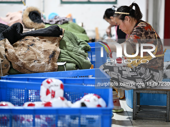 Workers make footballs by hand for export to overseas markets such as Japan at a sports goods factory in Suqian, Jiangsu province, China, on...